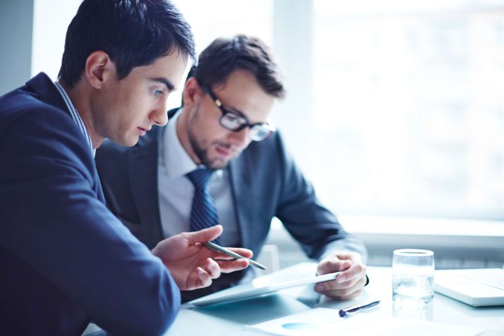 Serious businessman explaining data to his colleague at meeting