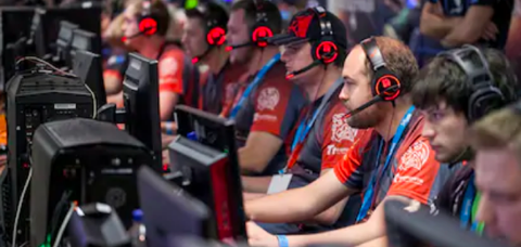 Online Gaming Support Team sitting with headsets in workplace and supporting gamers