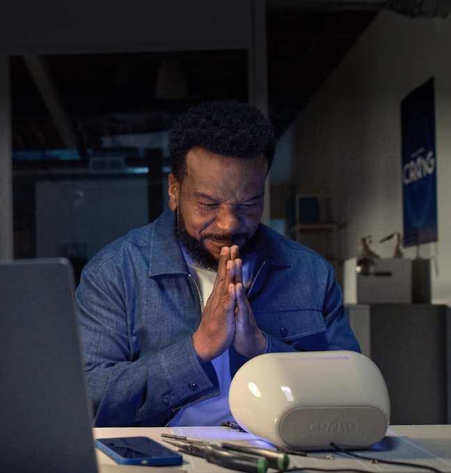 Craig seated, smiling and looking at the Wake Up with Craig alarm clock. His hands are pressed together in front of his face in a thank you/gratitude sign.