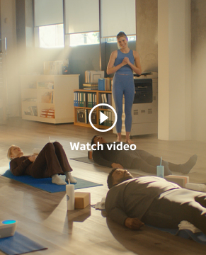 Set in a make-shift Yoga Studio, the Wake Up with Craig Team is in Shavasana pose while the instructor watches and smiles.